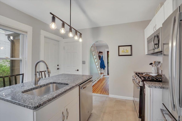 146 Summit St, Manchester, CT 06040 - kitchen featuring appliances with stainless steel finishes, arched walkways, white cabinetry, hanging light fixtures, and light stone counters