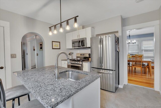 146 Summit St, Manchester, CT 06040 - kitchen featuring stainless steel appliances, arched walkways, white cabinets, a chandelier, and light stone counters