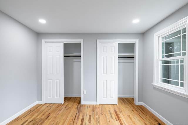 107 Meetinghouse Rdg, Meriden, CT 06450 - unfurnished bedroom featuring multiple closets, light wood-style flooring, recessed lighting, and multiple windows