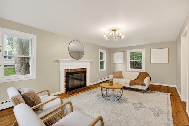 29 Bradford Dr, Windsor, CT 06095 - living area with wood finished floors, a chandelier, a brick fireplace, and baseboard heating