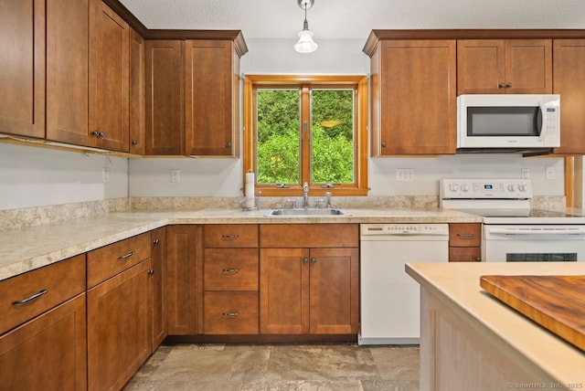 44 Brindlewood Path, Colchester, CT 06415 - kitchen featuring white appliances, light countertops, hanging light fixtures, brown cabinetry, and light stone finish floors