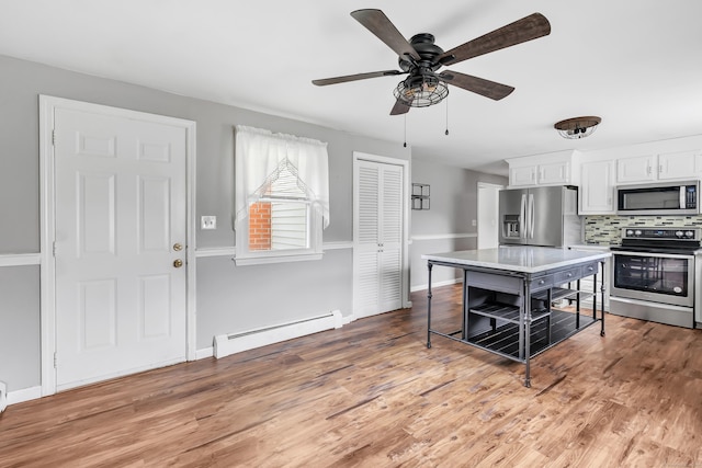 66 Bridgeport Ave, Bristol, CT 06010 - kitchen featuring stainless steel appliances, a baseboard radiator, white cabinets, backsplash, and light countertops