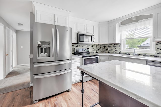 66 Bridgeport Ave, Bristol, CT 06010 - kitchen featuring stainless steel appliances, white cabinets, decorative backsplash, light wood-style flooring, and light stone countertops
