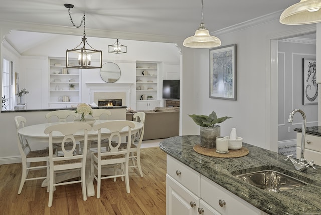 70 Fitch Ln, New Canaan, CT 06840 - dining space with light wood-style floors, crown molding, built in features, and a glass covered fireplace