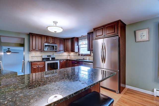 16 Kenwood Rd, Meriden, CT 06450 - kitchen featuring stainless steel appliances, light wood finished floors, backsplash, a ceiling fan, and dark stone countertops