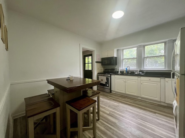 71 Forest Rd, West Haven, CT 06516 - kitchen with stainless steel range with gas cooktop, black microwave, dark countertops, white cabinetry, and freestanding refrigerator