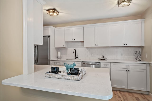 499 Heritage Vlg Unit B, Southbury, CT 06488 - kitchen with appliances with stainless steel finishes, white cabinetry, decorative backsplash, light wood-type flooring, and light stone countertops