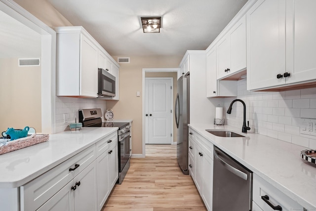 499 Heritage Vlg Unit B, Southbury, CT 06488 - kitchen featuring stainless steel appliances, light wood-style flooring, white cabinets, light countertops, and tasteful backsplash