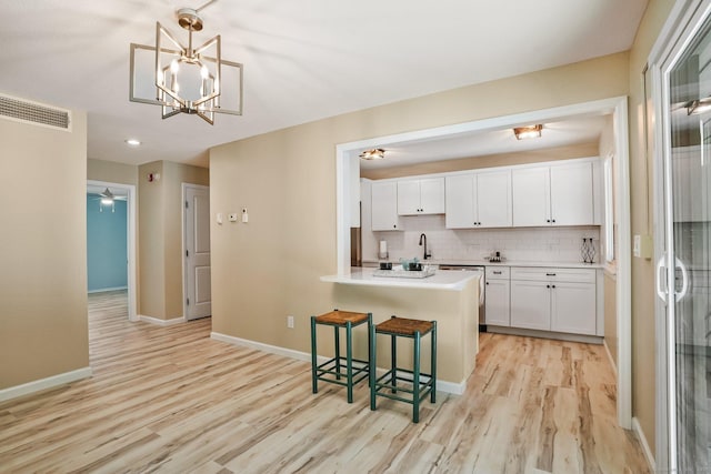 499 Heritage Vlg Unit B, Southbury, CT 06488 - kitchen featuring light wood-style floors, white cabinetry, a breakfast bar area, and light countertops