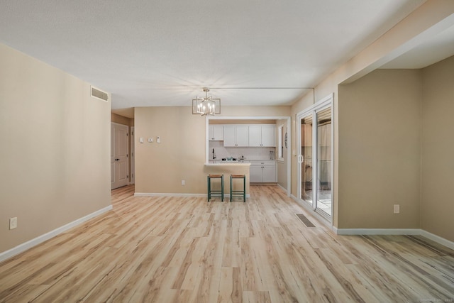 499 Heritage Vlg Unit B, Southbury, CT 06488 - unfurnished living room with light wood-style flooring and a chandelier