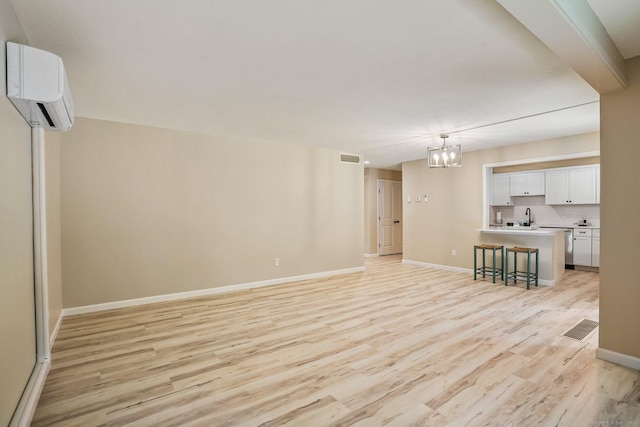 499 Heritage Vlg Unit B, Southbury, CT 06488 - unfurnished living room featuring a wall unit AC, light wood-style flooring, and a chandelier