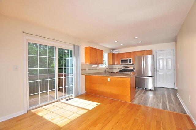 19 Windy Hill Ln Unit 19, Rocky Hill, CT 06067 - kitchen featuring appliances with stainless steel finishes, light wood-type flooring, a peninsula, brown cabinets, and decorative backsplash