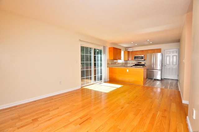19 Windy Hill Ln Unit 19, Rocky Hill, CT 06067 - kitchen with appliances with stainless steel finishes, open floor plan, light wood-type flooring, a peninsula, and brown cabinets