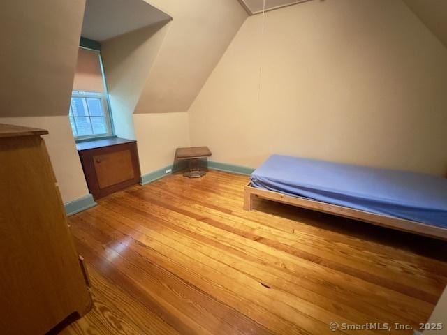118 Sims St, Bridgeport, CT 06604 - unfurnished bedroom with wood finished floors, vaulted ceiling, and attic access