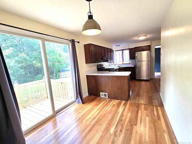 266 Cianci Rd, New Britain, CT 06053 - kitchen with appliances with stainless steel finishes, light wood-type flooring, a peninsula, dark brown cabinets, and light countertops