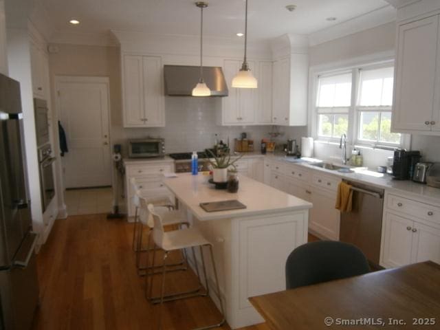 65 Sherwood Pl Unit 65, Greenwich, CT 06830 - kitchen featuring appliances with stainless steel finishes, ventilation hood, white cabinets, light countertops, and a kitchen island