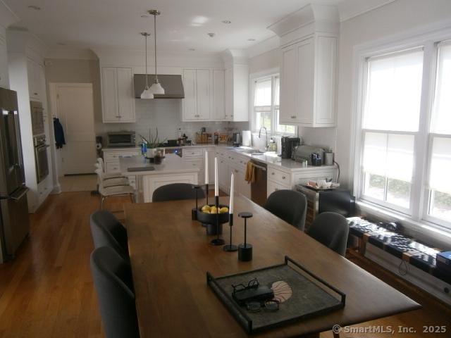 65 Sherwood Pl Unit 65, Greenwich, CT 06830 - kitchen with stainless steel appliances, extractor fan, white cabinets, a center island, and decorative light fixtures