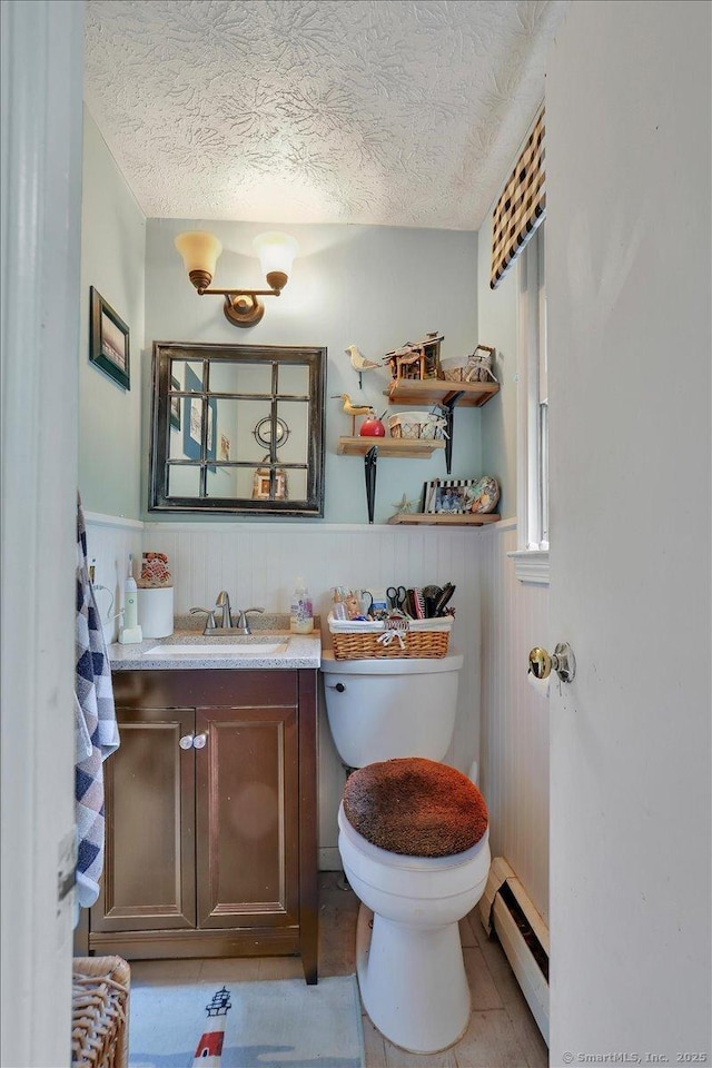 25 Ridgewood Rd, Willington, CT 06279 - half bath with a baseboard radiator, vanity, a wainscoted wall, and a textured ceiling