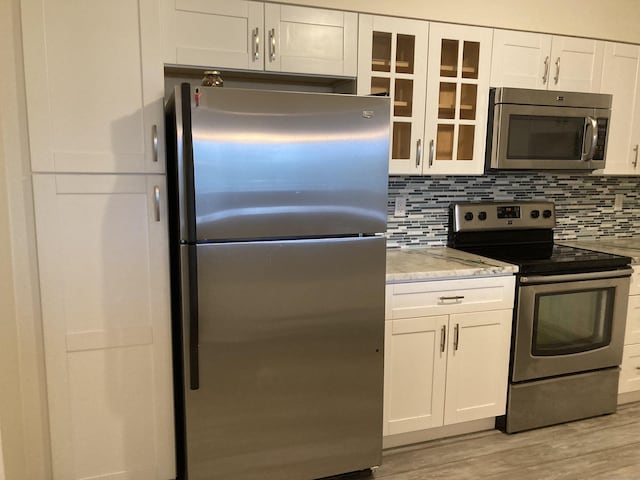 50 Birdseye St Unit 104, Stratford, CT 06615 - kitchen featuring appliances with stainless steel finishes, white cabinetry, light wood-style flooring, and glass insert cabinets