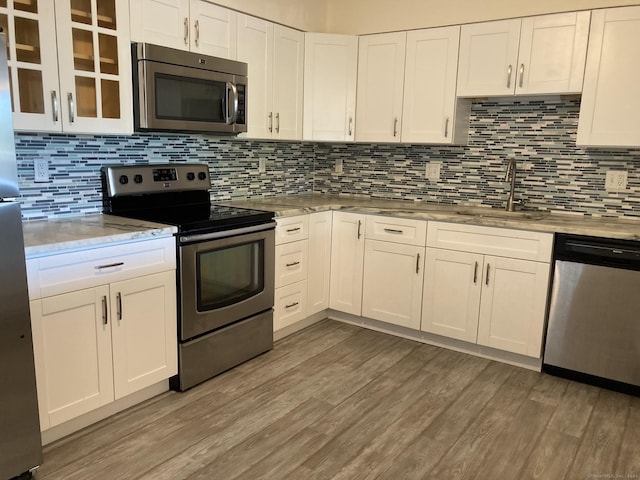 50 Birdseye St Unit 104, Stratford, CT 06615 - kitchen featuring stainless steel appliances, light wood finished floors, white cabinets, and backsplash