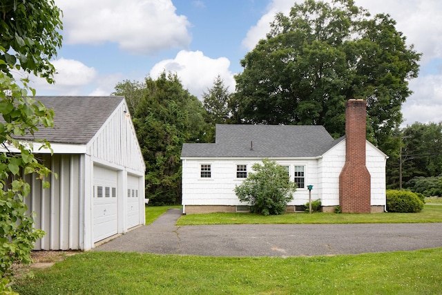 367 Norfolk Rd, North Canaan, CT 06024 - view of front facade featuring a chimney, a detached garage, an outbuilding, roof with shingles, and a front lawn