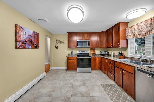 266 Ballfall Rd, Middletown, CT 06457 - kitchen featuring stainless steel appliances, a baseboard radiator, arched walkways, light tile patterned flooring, and brown cabinets