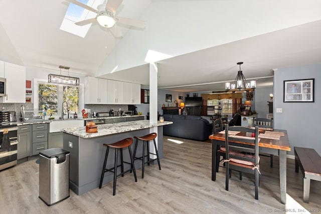 31 Bob White Way, Plainfield, CT 06354 - kitchen with stainless steel appliances, a ceiling fan, light wood-type flooring, tasteful backsplash, and a breakfast bar area