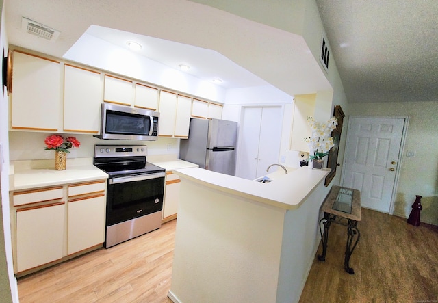 59 Leafwood Ln Apt 275, Groton, CT 06340 - kitchen with appliances with stainless steel finishes, light wood-style floors, a peninsula, white cabinetry, and a kitchen bar