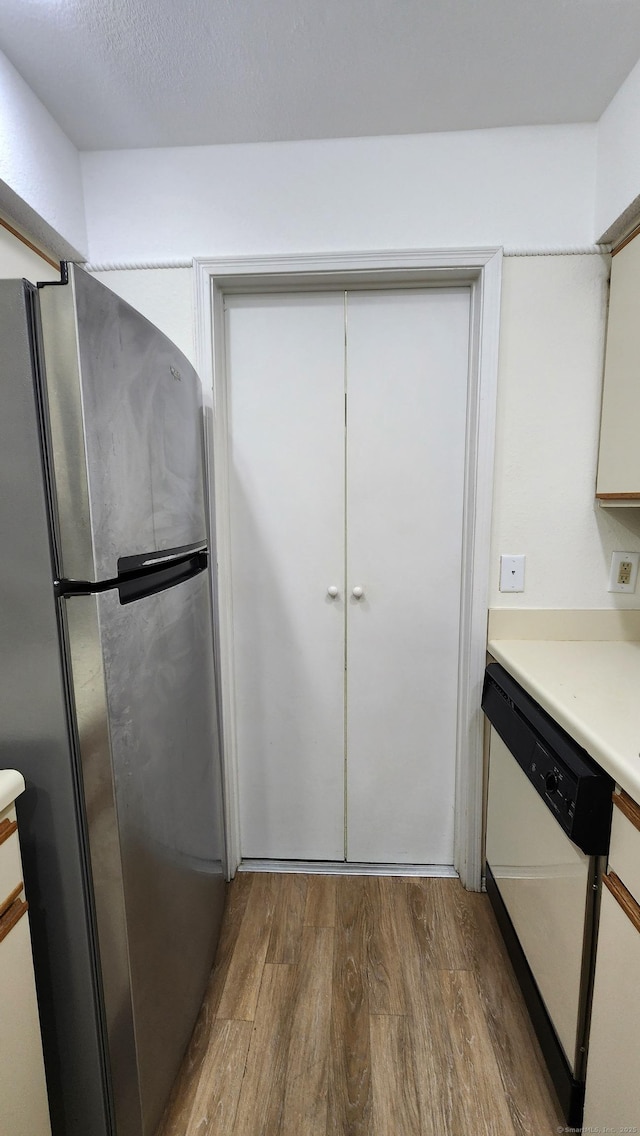 59 Leafwood Ln Apt 275, Groton, CT 06340 - kitchen with freestanding refrigerator, white dishwasher, wood finished floors, light countertops, and white cabinetry