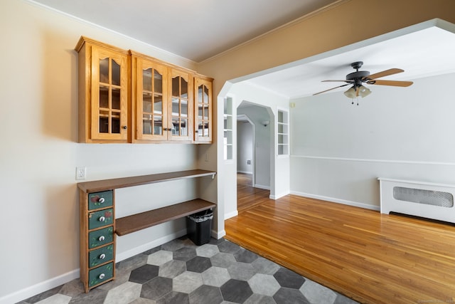 6 French St, Bristol, CT 06010 - kitchen with a ceiling fan, glass insert cabinets, crown molding, arched walkways, and dark wood-type flooring