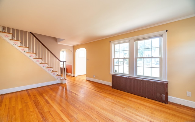 44 Middle Tpke E, Manchester, CT 06040 - entryway featuring radiator heating unit, arched walkways, light wood finished floors, crown molding, and stairway