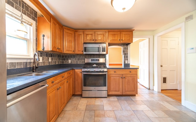 44 Middle Tpke E, Manchester, CT 06040 - kitchen with stainless steel appliances, backsplash, brown cabinetry, dark countertops, and light stone finish flooring