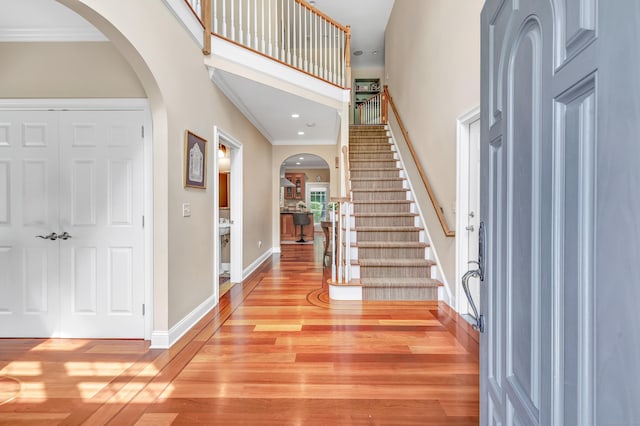 19 Woodlawn Dr, Trumbull, CT 06611 - entryway featuring arched walkways, light wood-style floors, a high ceiling, stairs, and ornamental molding