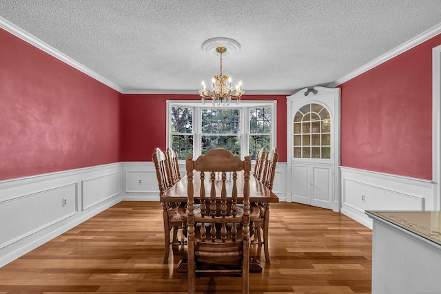 7 Sharon Ln, Old Saybrook, CT 06475 - dining area with a chandelier, a wainscoted wall, a textured ceiling, wood finished floors, and crown molding