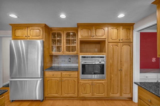 7 Sharon Ln, Old Saybrook, CT 06475 - kitchen featuring stainless steel appliances, glass insert cabinets, dark stone countertops, light wood finished floors, and recessed lighting