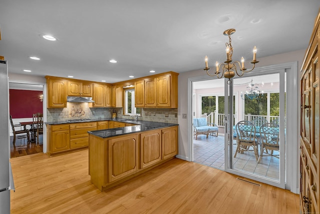 7 Sharon Ln, Old Saybrook, CT 06475 - kitchen with under cabinet range hood, a chandelier, light wood-style floors, stainless steel gas cooktop, and healthy amount of natural light