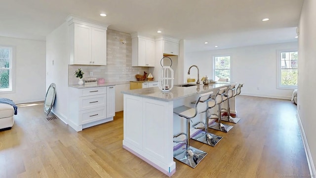 12 Woodland Dr, Milford, CT 06460 - kitchen featuring light wood-style floors, recessed lighting, white cabinetry, tasteful backsplash, and a kitchen breakfast bar