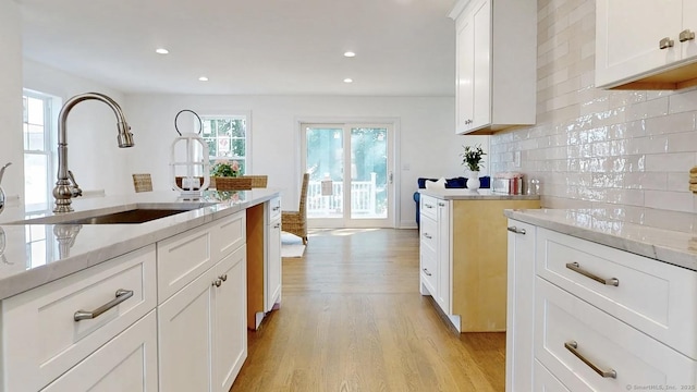 12 Woodland Dr, Milford, CT 06460 - kitchen with light wood-style floors, backsplash, recessed lighting, white cabinets, and light stone counters