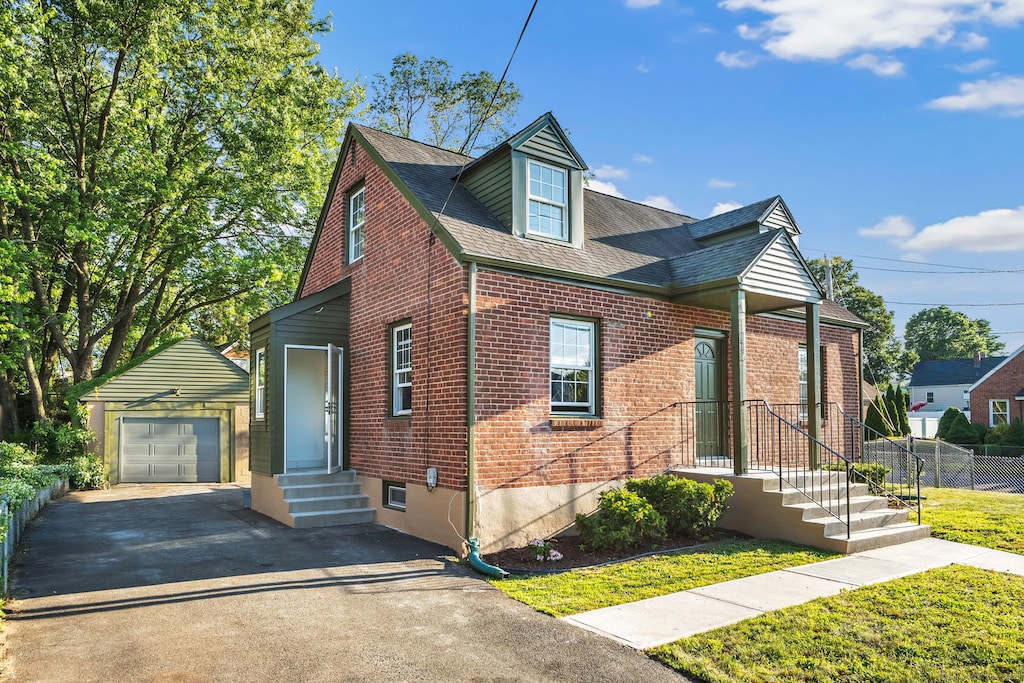 116 Morse St, Hamden, CT 06517 - view of front of home with brick siding, asphalt driveway, an outdoor structure, a detached garage, and roof with shingles