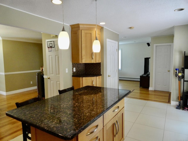17 Ridge View Ter, New Hartford, CT 06057 - kitchen featuring a baseboard heating unit, pendant lighting, dark stone countertops, a center island, and light tile patterned flooring