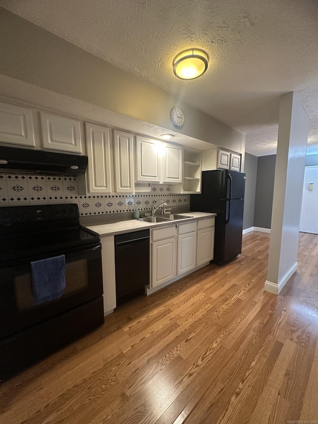 65 Horse Pond Rd Apt G, Salem, CT 06420 - kitchen with black appliances, under cabinet range hood, a textured ceiling, light wood-style floors, and white cabinetry
