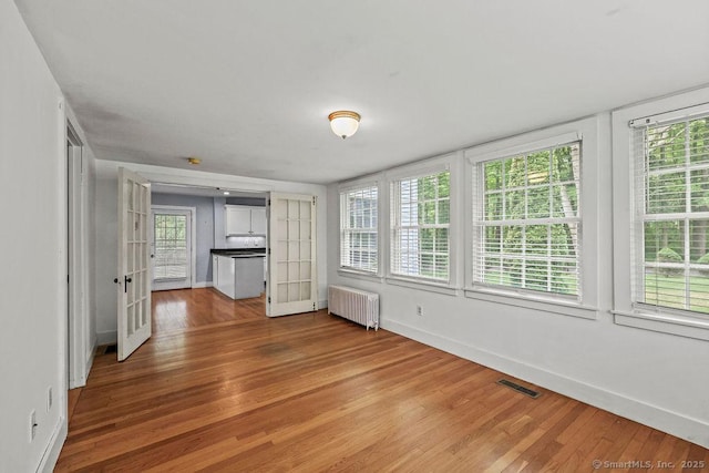 88 Powder Hill Rd, Middlefield, CT 06455 - unfurnished living room with radiator, light wood-type flooring, and plenty of natural light