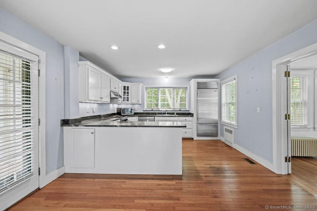 88 Powder Hill Rd, Middlefield, CT 06455 - kitchen with radiator heating unit, stainless steel appliances, a peninsula, dark countertops, and white cabinetry
