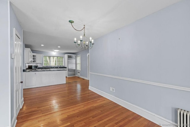 88 Powder Hill Rd, Middlefield, CT 06455 - kitchen featuring dark countertops, radiator heating unit, a chandelier, light wood finished floors, and white cabinetry