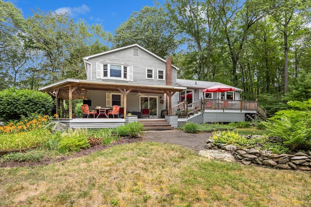 rear view of property featuring a chimney and a lawn