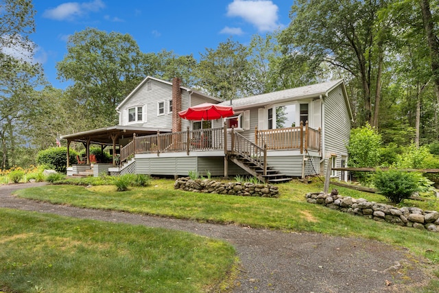 view of front facade featuring stairway, a chimney, a wooden deck, and a front lawn