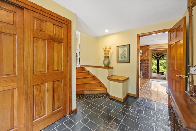 entrance foyer featuring recessed lighting, stairs, and dark stone finish floors