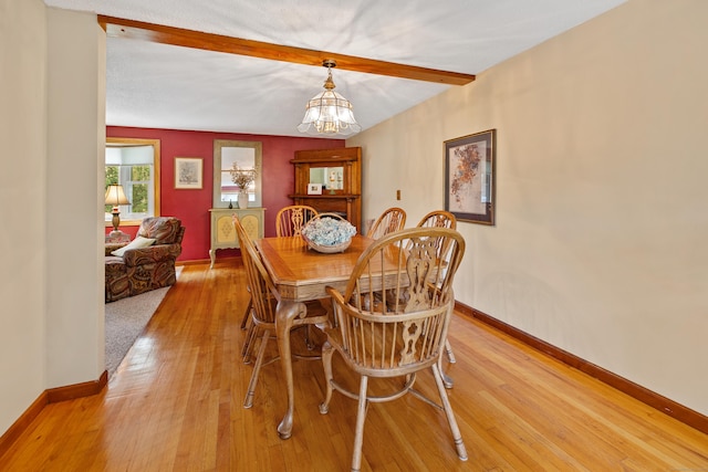 dining area featuring beam ceiling, a chandelier, and light wood-style floors