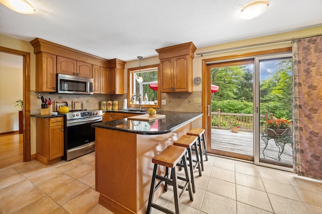 kitchen featuring stainless steel appliances, plenty of natural light, backsplash, a breakfast bar area, and a textured ceiling