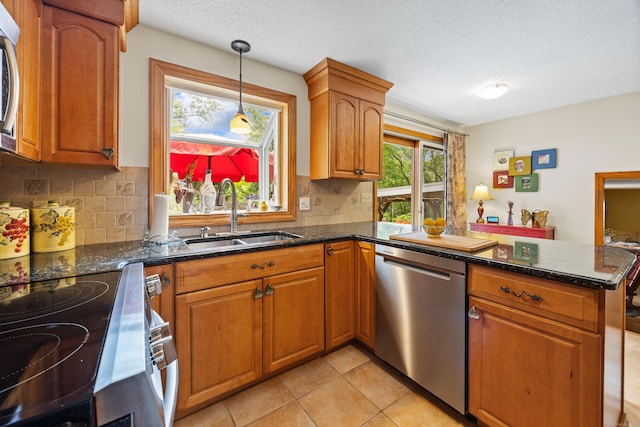 kitchen with stainless steel appliances, a peninsula, tasteful backsplash, brown cabinets, and a textured ceiling